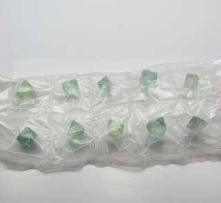 This set of 10 octahedron is unpolished and mostly transparent green 