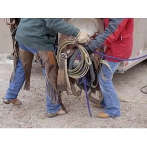 Ranch Couple Work Together to Lift a Saddle into a Trailer Stretched 