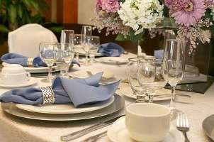   formal table setting with blue napkins and centerpiece of real flowers